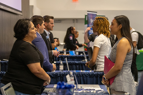 Students lined up at tables speaking to employers