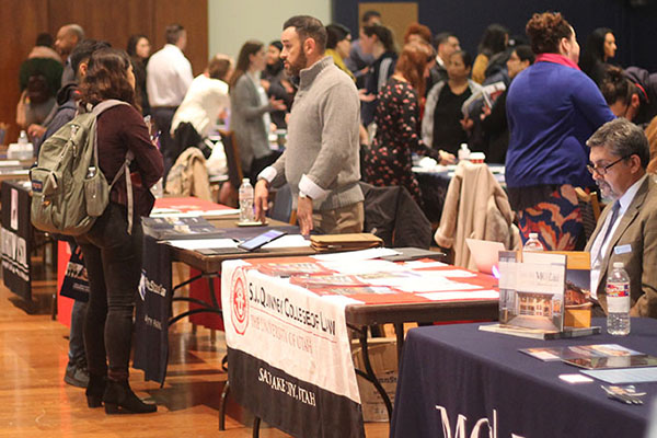 Law schools at tables in a large room with students interacting with school reps